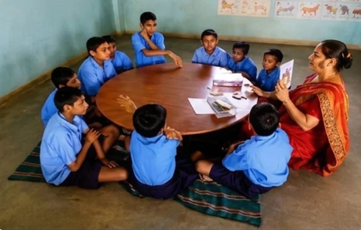 A teacher showing a picture card to students around a classroom table